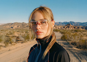 Woman wearing clear sports glasses outdoors in a desert landscape.